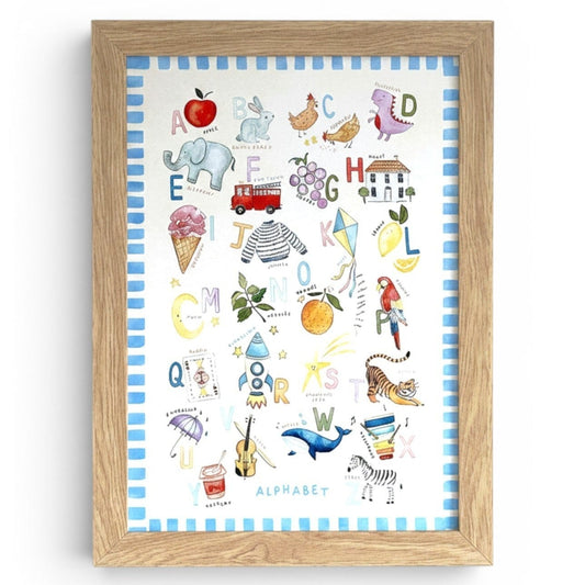 School Bus Studio illustrated alphabet nursery wall art print with hand-painted A-Z icons in a light wood frame.
